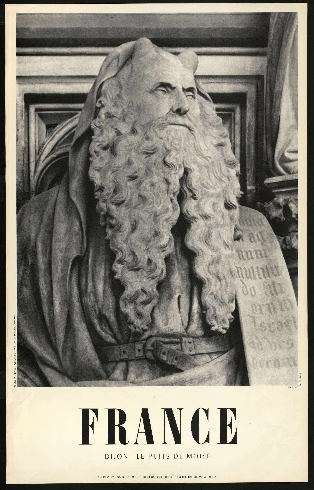 Une affiche en noir et blanc contenant la photo du visage d'une sculpture de Moïse occupe les deux tiers de l'affiche, le mot "France" apparaît en dessous en grandes lettres capitales puis en plus petit est inscrit "Dijon le puits de Moïse, direction générale du tourisme"